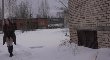 Valya pulls down her leggings to take an urgent piss in the snow by a building