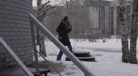 White girl pulls down her jeans to pee in the snow behind a building
