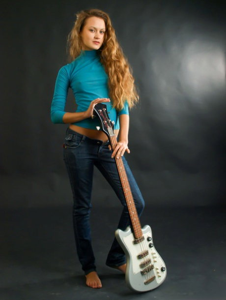18-year-old girl Karissa P holds a bass guitar while getting totally naked