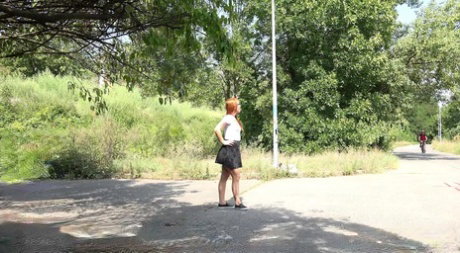 Redhead Foxy Sanie takes a pee on a rural road while a cyclist goes past