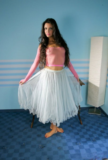 Young girl with long hair Isabella hikes up her skirt before getting naked