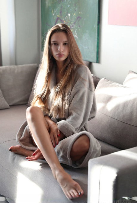 Young beauty Elin slips off her robe and lingerie to model naked in soft light