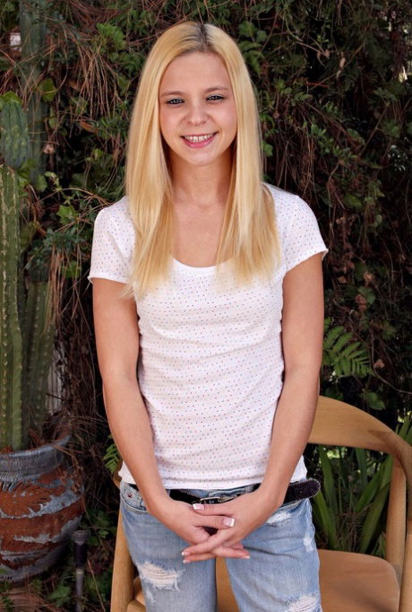 Blonde teen strips to her sandals on an outdoor chair amid the foliage