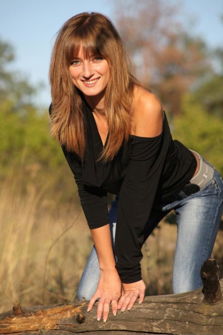 Nice teen with long hair and a smile stands naked in the woods