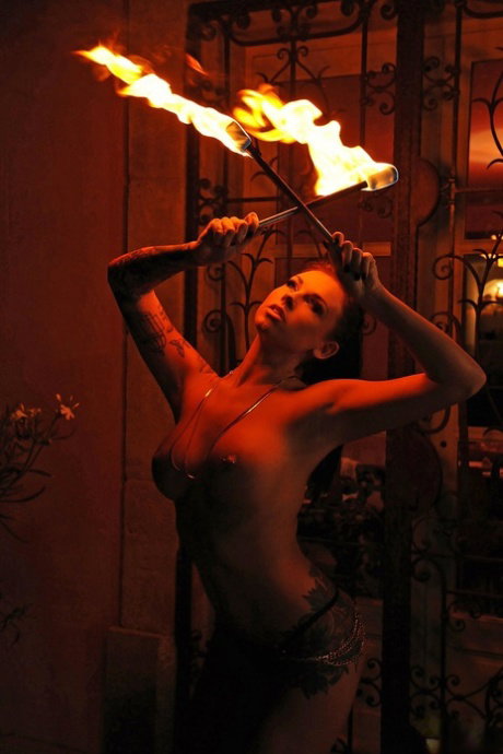 Femdom Daniela gives an outdoor fire-play performance with her big boobs bared