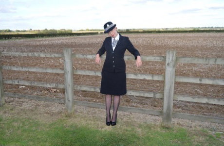 Mature policewoman Barby Slut removes her uniform against a fence at a farm