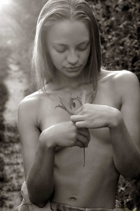Young girl with a smiley face plays with the soft petals of a flower