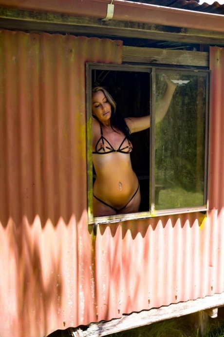 Brunette MILF Roxeanne models a revealing bikini in a shack