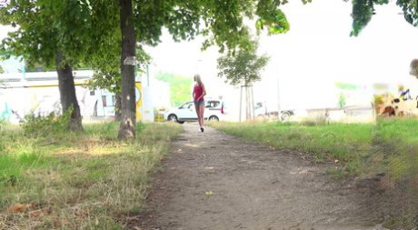 Blonde girl Debora pees on a dirt path during the middle of a sunny day