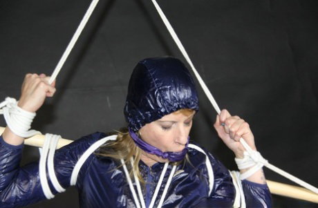 Amateur model Pia is restrained and gagged while wearing a raincoat