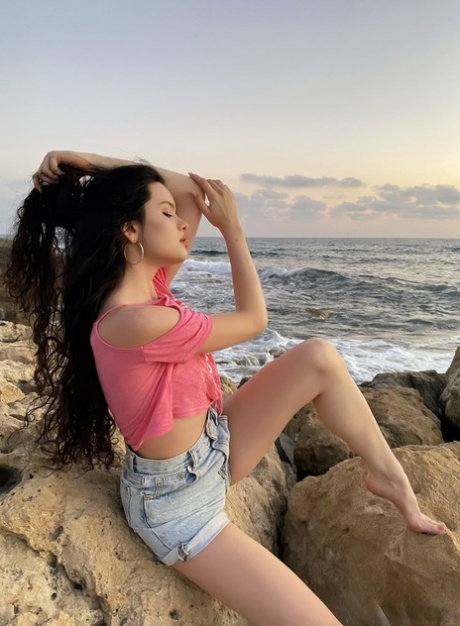 Pretty brunette teen Ariana Mun sports a touch of lipstick while posing nude