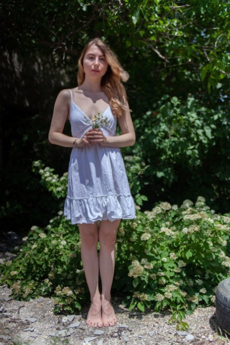 Barely legal girl models totally naked in a bushy area on a sunny day