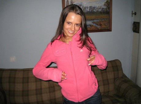 Brunette amateur unveils her skinny body while getting naked on a sofa