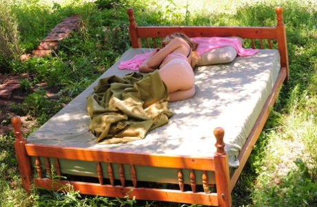 Solo girl Angie N gets naked to masturbate on a bed in a backyard