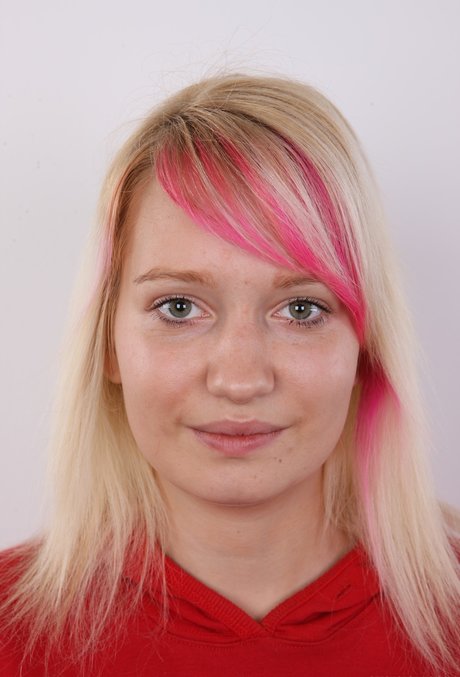 Young blonde girl with dyed hair removes her clothing for her first nude shoot