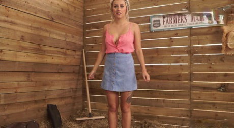 Farm girl exposes her fake tits while kneeling on straw inside a stall