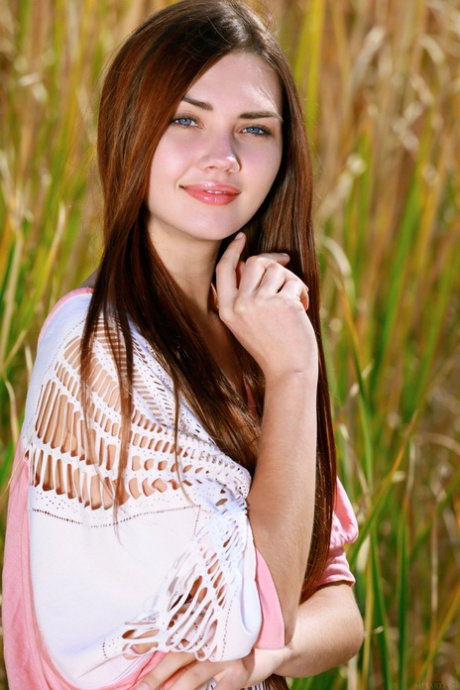Nice teen with long hair gets completely naked in tall grasses