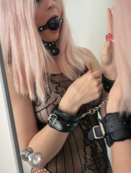 Young girl sports a ball gag and mesh bodystocking while masturbating