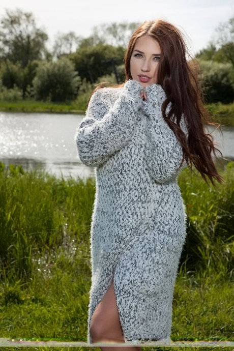 Beautiful female Niemira removes a knitted dress to pose nude in a field
