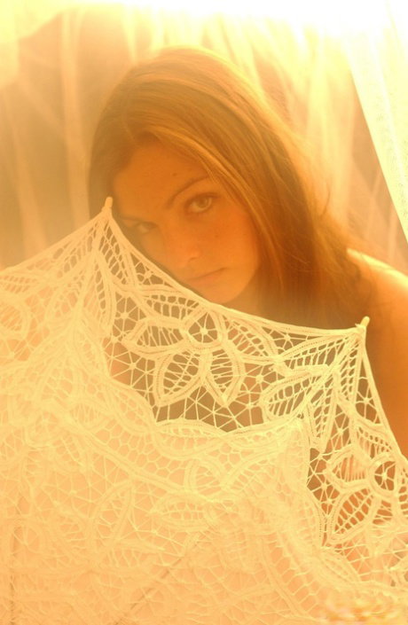 Solo girl holds an umbrella while topless under a canopy of tulle