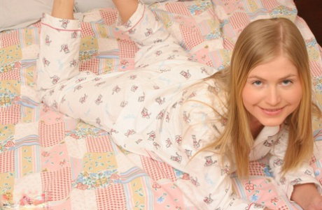 Young looking blonde Malina removes her pyjamas while masturbating on a bed