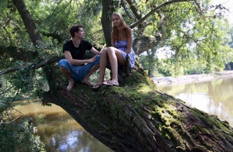 Young lovers have sexual intercourse on a tree limb over a body of water