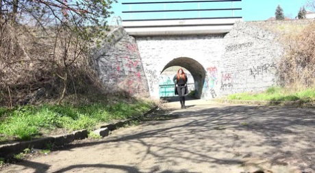 Redheaded teen Katy Rose takes a piss on a paved road during the day