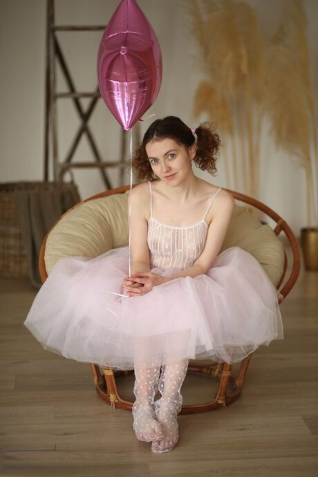 Sweet teen Suzy holds a balloon while getting completely naked