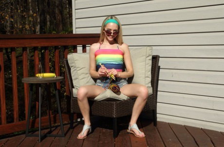 Blonde teen Lily Larimar eats a banana during vaginal insertions on a deck