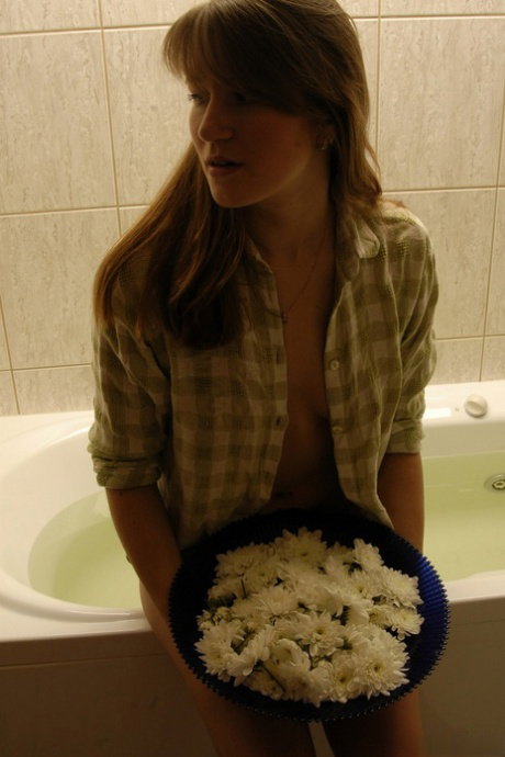 Nice teen with a phat ass shows her bald twat while taking a bath in flowers