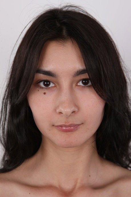 Amateur model with dark hair stands naked before a close-up of her bald cunt