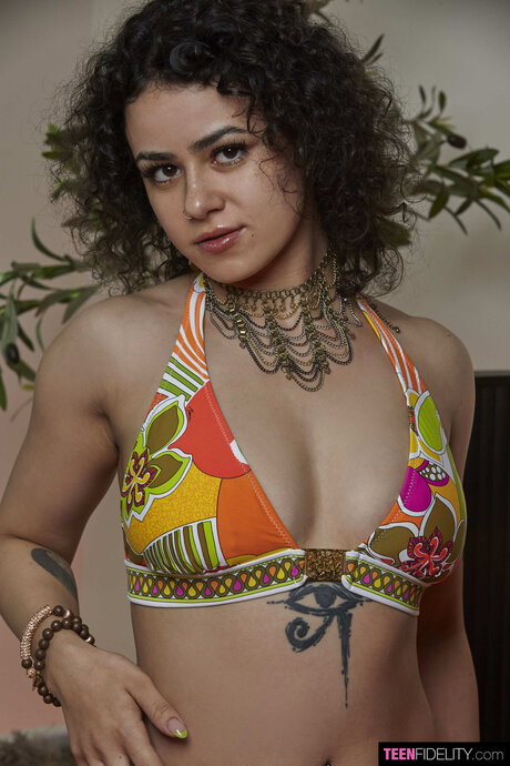 Tattooed teen with curly hair gets banged by a man on a bed