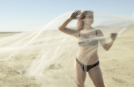Redheaded girl Melody Jordan takes off her bra and panty set on a dry lake bed