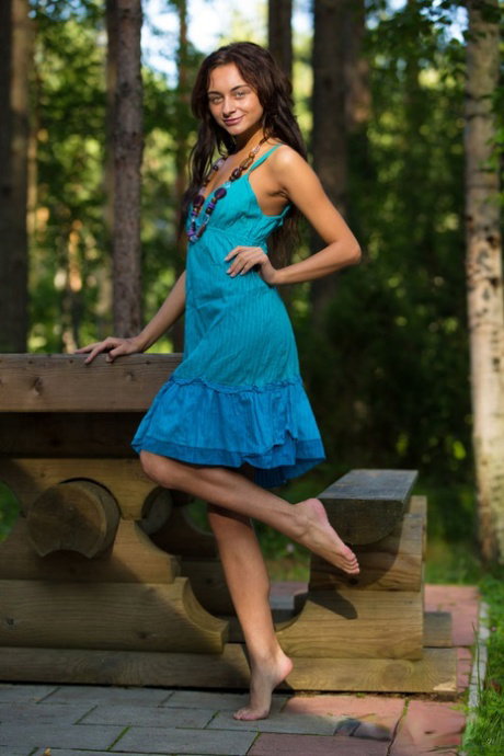 Barely legal model Dolores M slips off a dress to pose nude by a picnic table