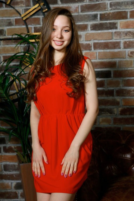 Beautiful teen with long hair and big boobs gets totally naked on a leather sofa
