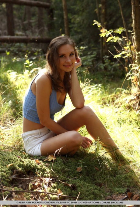 Nice teen Galina A bares her tight ass as she gets naked on forest floor