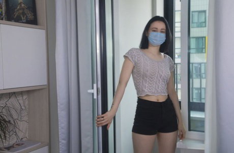 Young brunette Sheril doffs a surgical mask and clothing before masturbating