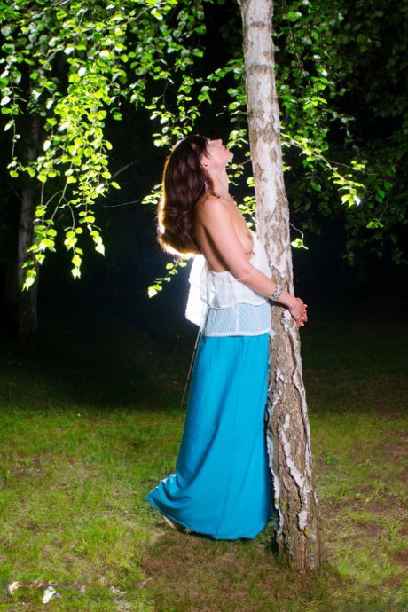 Sexy MILF Jeny Smith strips to her heels and poses by a tall tree