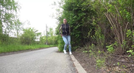 Clothed girl pulls down ripped jeans for a pee while bicyclists pass by her