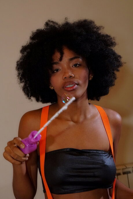 Cute black teen with a big afro masturbates with a sex toy on a bed