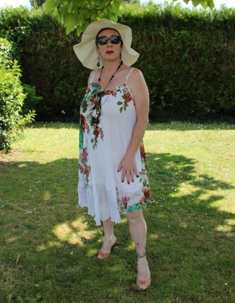 Mature amateur Mary Bitch pulls down her thong on a lawn in a sun hat