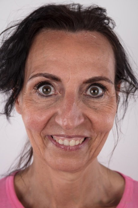 Mature woman Klaudie stands naked after removing her clothing in solo action