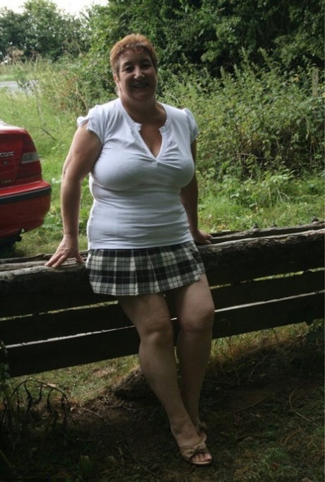 Fat British lady Kinky Carol unleashes her large breasts over a rustic fence