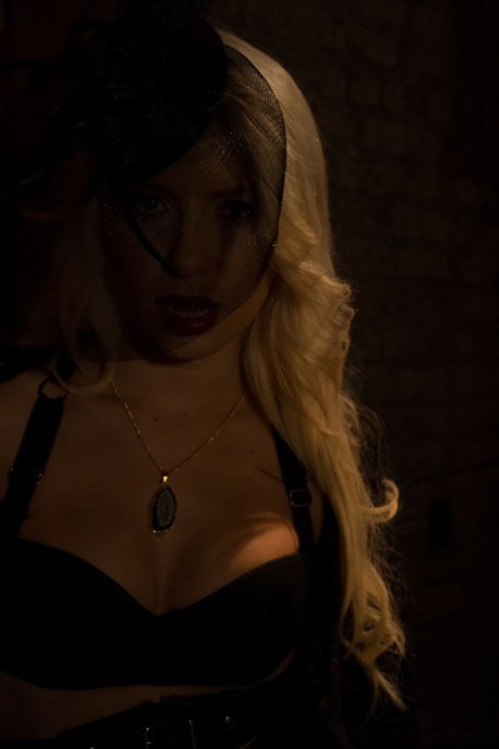 Blonde vampire exposes her fangs and boobs in a poorly lit cellar
