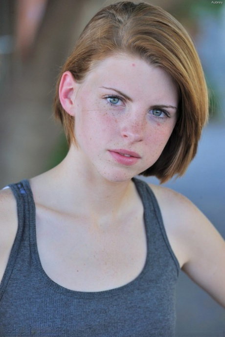 Redhead teen Aubrey shyly takes her time stripping off on the street