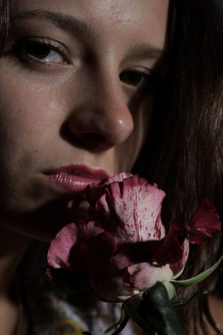 Solo girl holds a pink rose while getting totally naked during a SFW shoot
