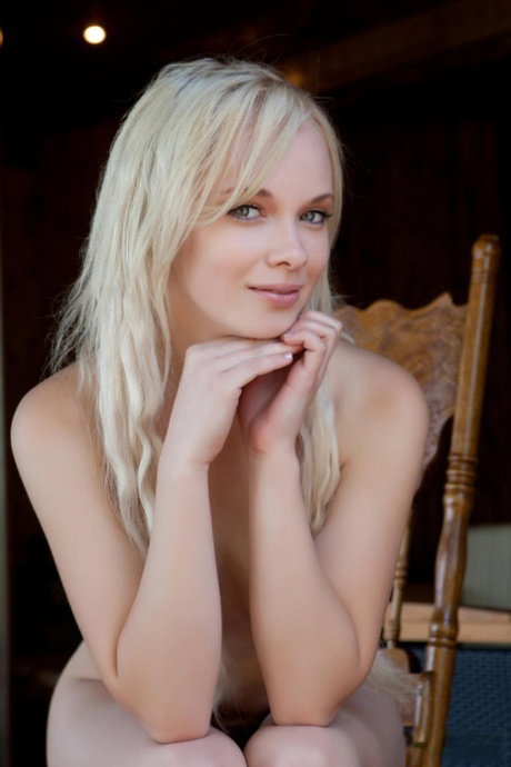 Charming blonde teen Feeona models naked on a wooden chair up at the cottage