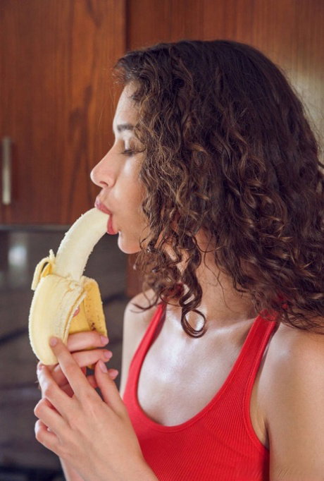 Young girl with wavy brunette hair Cristin gets naked after eating a banana