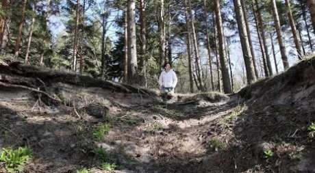 Brunette chick Katy Dee takes a badly needed pee over a bank in the woods