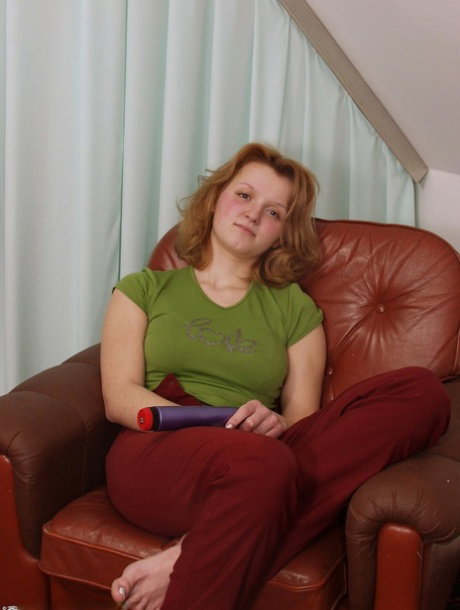 Natural redhead gets naked while masturbating with a vibrator on a chesterfield